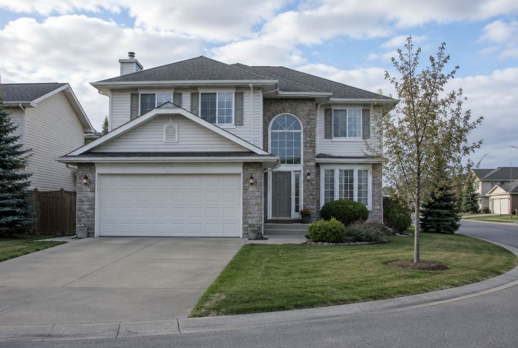 A 1990s two-storey family home with a front attached double garage and an arched window over the entry