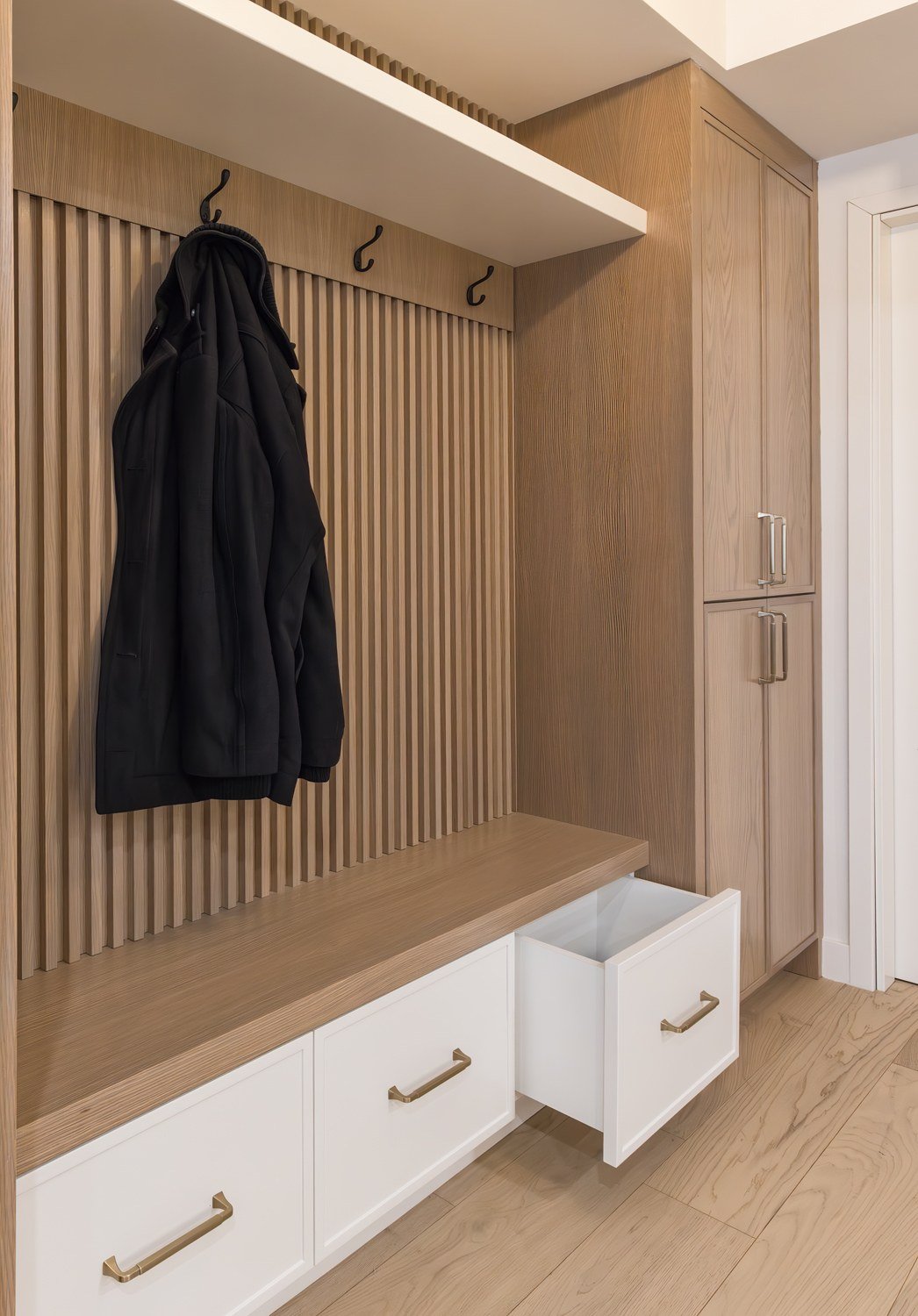 Mudroom millwork with slatted wood wall and bench at the Kay2 Showroom